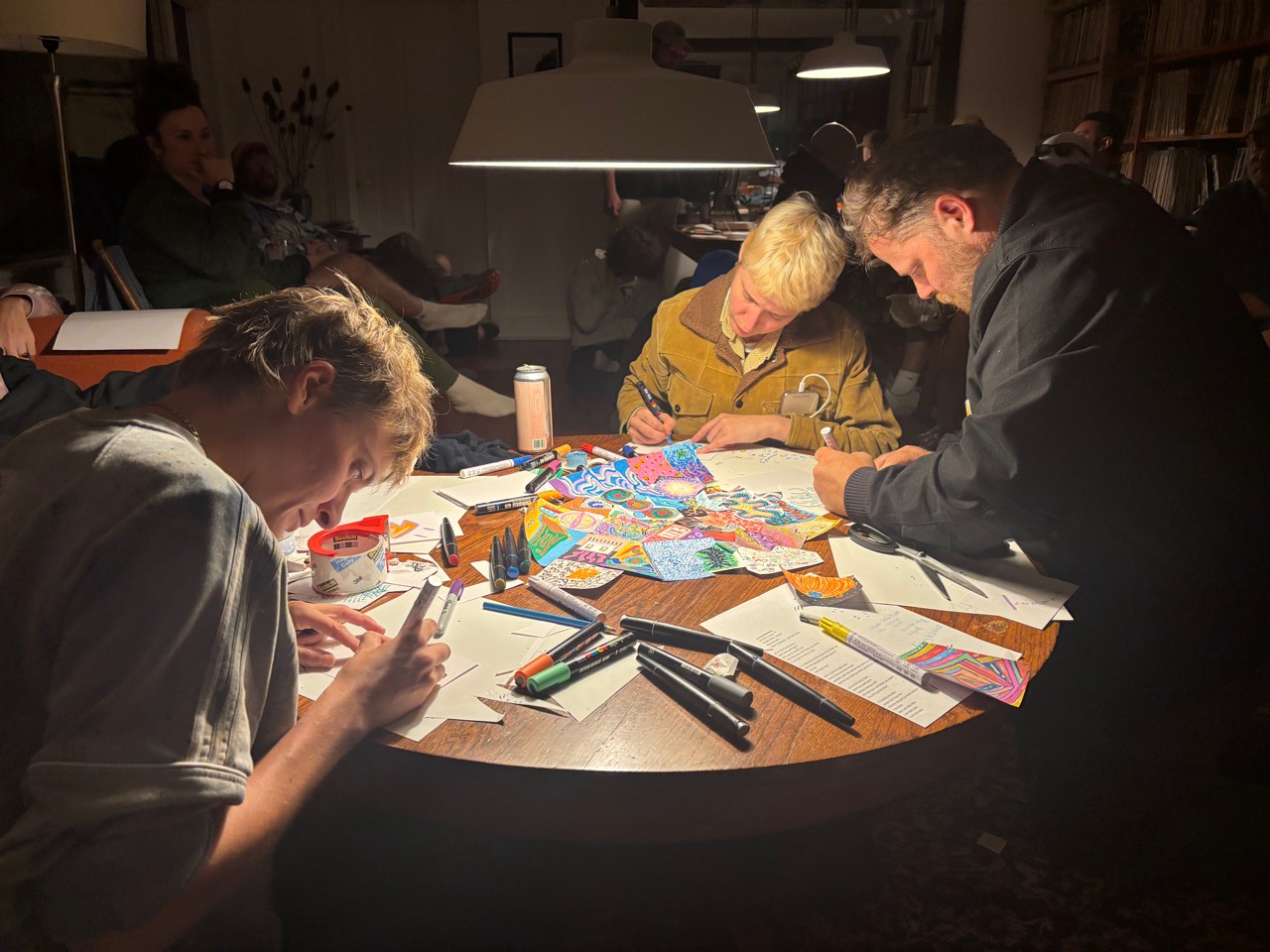 People drawing around a table during Exquisite Corpse